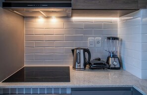 A modern kitchen with a built-in stove, a kettle, and a blender on the countertop. - Stylish Hassler One-Bedroom with Pool, Gym (Asunción)