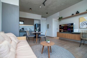 A modern living room with a sofa, chairs, a coffee table, and a dining area with a table and chairs. - Stylish Hassler One-Bedroom with Pool, Gym (Asunción)