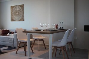 Un comedor moderno con una mesa rectangular, cuatro sillas blancas y un elemento decorativo en la pared.