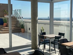 Ein Balkon mit Tisch und Stühlen, Blumentöpfen und einer Treppe zu einer höheren Ebene.