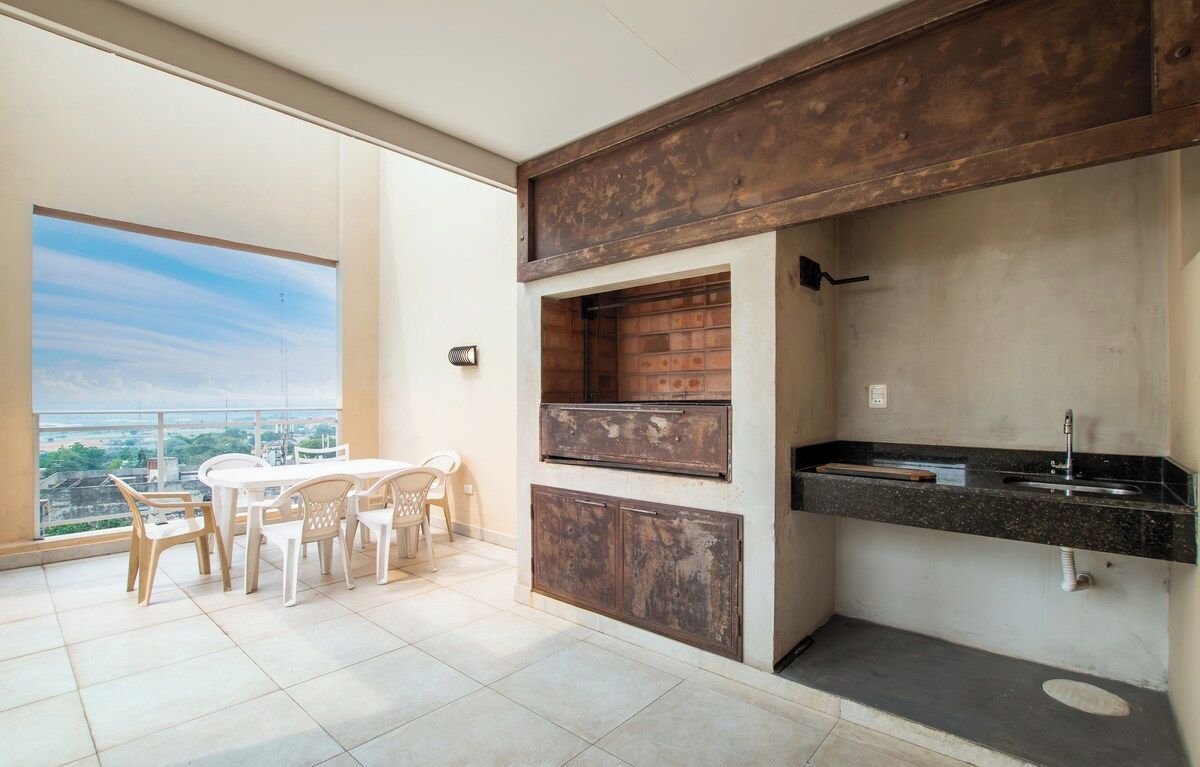 A balcony with a dining area, a built-in brick oven, and a kitchen counter with a sink.