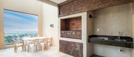 A balcony with a dining area, a built-in brick oven, and a kitchen counter with a sink.