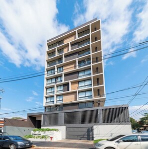 A multi-story building with balconies, a gated entrance, and a clear sky. - Modern Apartment, Workspace & Gym, Fast Wi-Fi (Asunción)