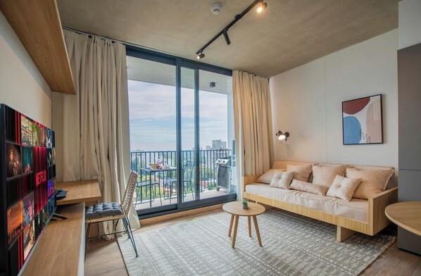 A modern living room with a sofa, a coffee table, a bookshelf, and a large window with curtains. - Modern Apartment, Workspace & Gym, Fast Wi-Fi (Asunción)
