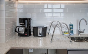 A kitchen with a coffee maker, toaster, and a sink with a drying rack. - Modern Apartment, Workspace & Gym, Fast Wi-Fi (Asunción)