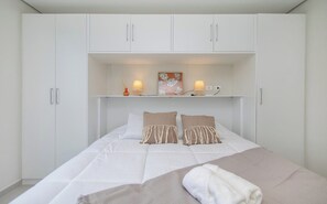 A bedroom with a bed, two bedside lamps, a nightstand, and a wall-mounted shelf with decorative items. - Charming Corporate Hub with Pool, Gym & Workspace (Asunción)