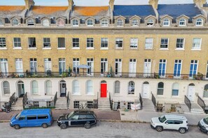 A row of terraced houses with a red door, a bicycle, and parked cars.