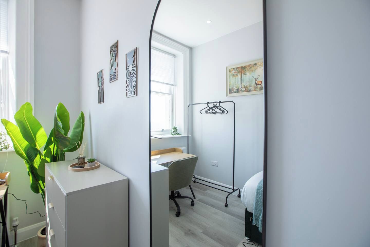 Un dormitorio moderno con escritorio, silla y perchero.