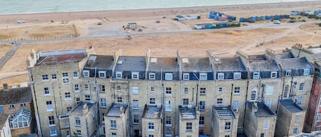 A multi-story building with a flat roof, located near a beach.