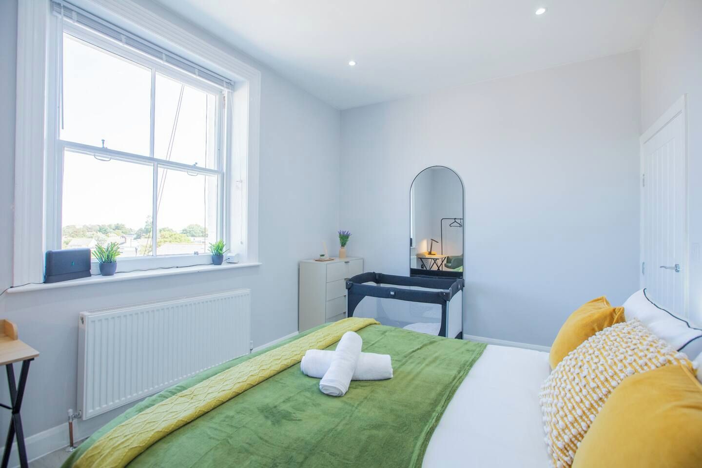 A bedroom with a bed, a dresser, a mirror, and a window.