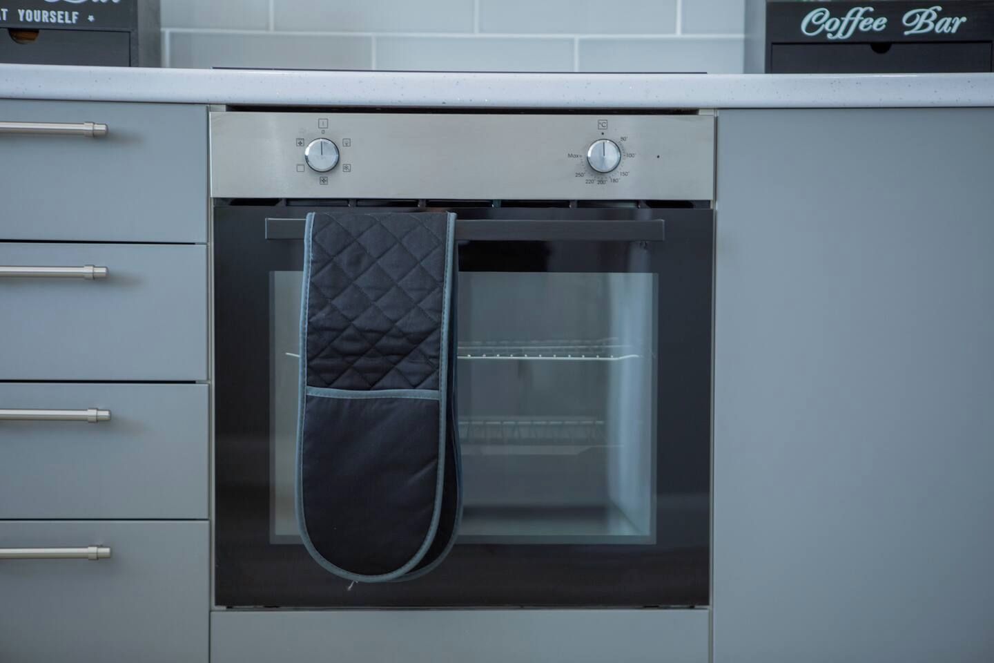 Eine Küche mit Backofen, einer Kaffeestation und einem aufgehängten Topflappen.