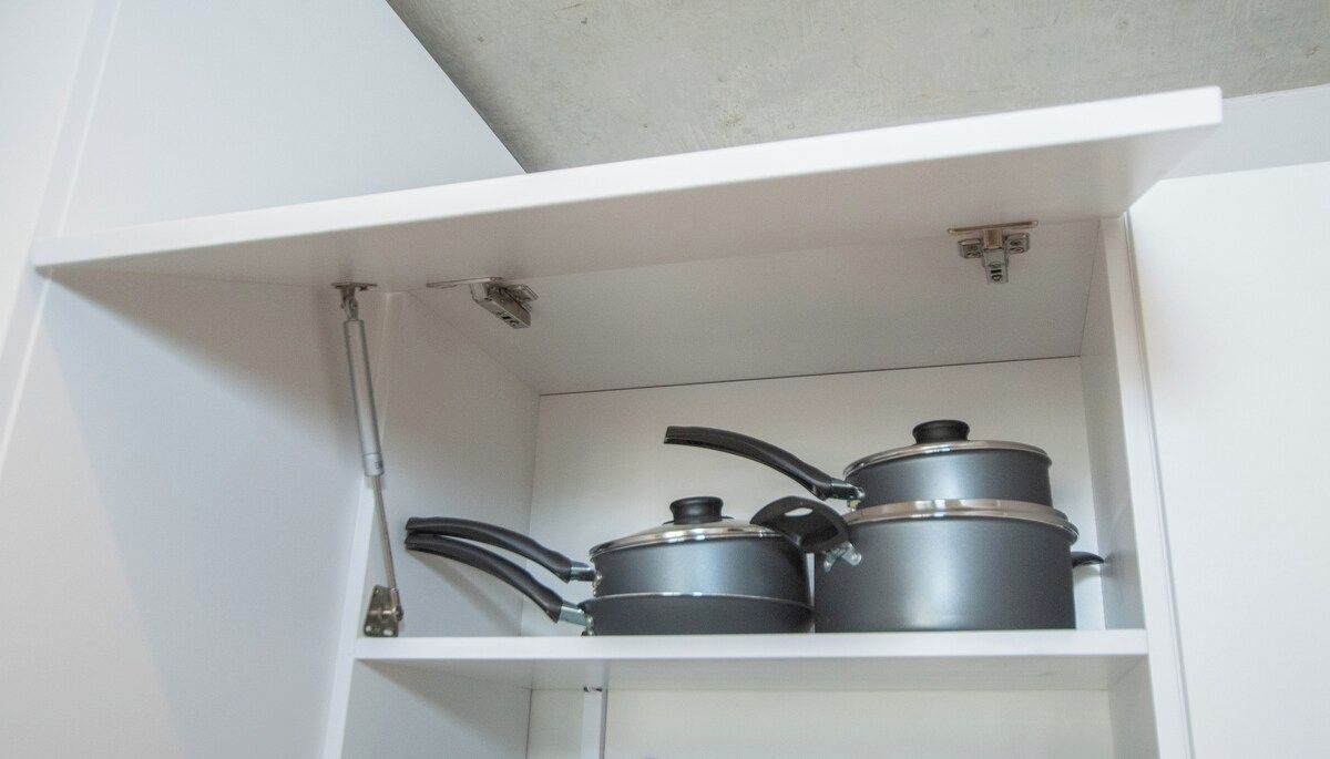 A kitchen cabinet with pots and pans.