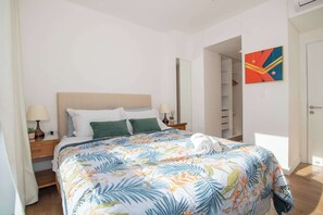 Ein Schlafzimmer mit einem Bett, Nachttischen, einem Spiegel, einem Kleiderschrank und einem farbenfrohen abstrakten Gemälde.