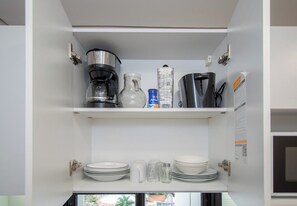 A kitchen with a coffee maker, a blender, and various kitchenware on the shelves. - Chic One-BR in a Prime Location with Pool and Gym (Asunción)