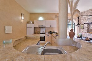Una cocina con un lavamanos curvo peculiar, una estufa y un refrigerador.