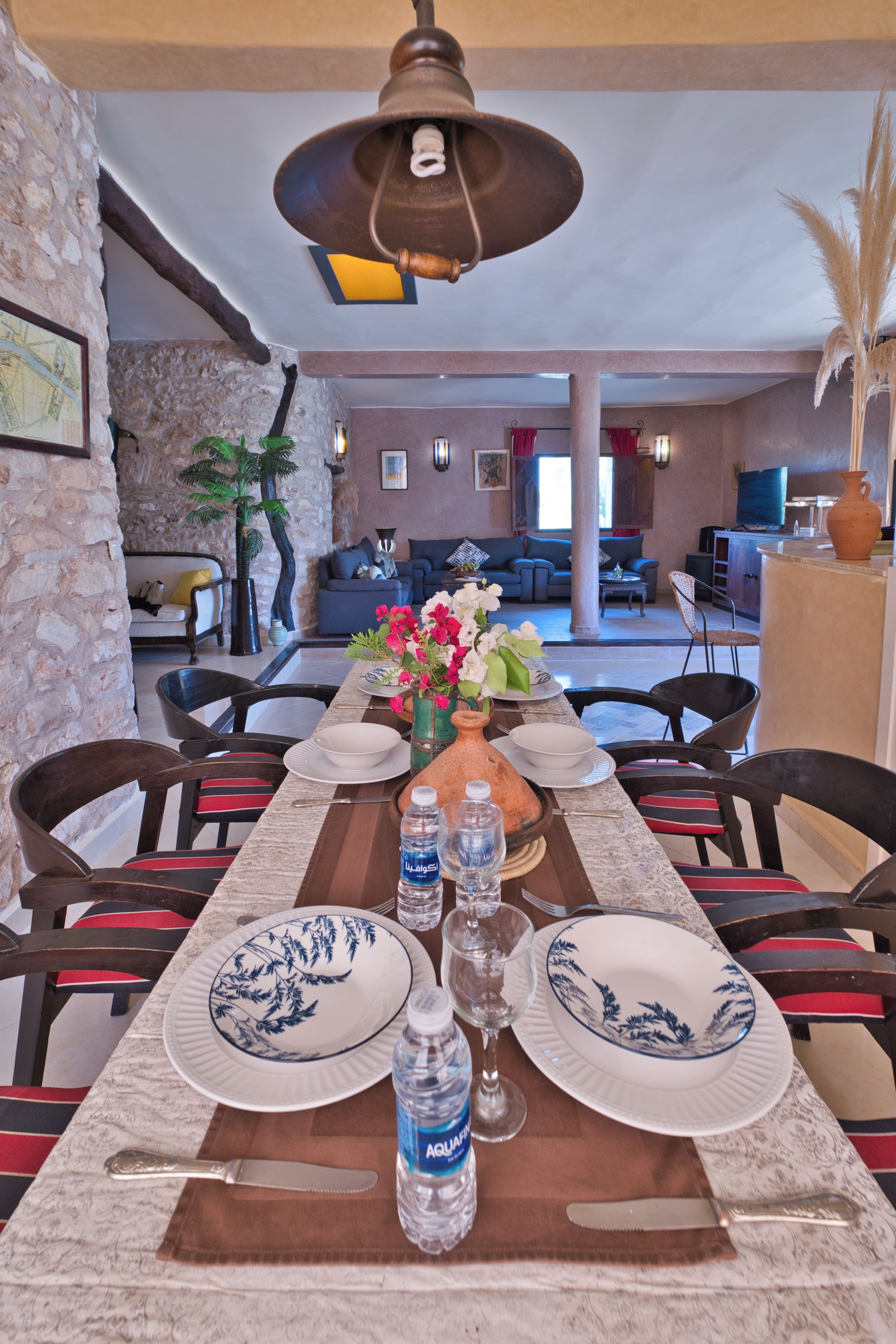 A dining area with a long table set for a meal, surrounded by chairs.