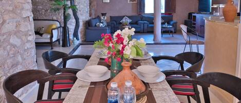 A dining area with a long table set for a meal, surrounded by chairs.