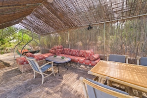 An outdoor seating area with a woven canopy, a sofa set, and a table with chairs. - Private Villa & Nature - Domaine l'Oliveraie (Essaouira)