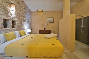 A room with a bed, a stone wall, a framed picture, a nightstand, and a shower. - Private Villa & Nature - Domaine l'Oliveraie (Essaouira)
