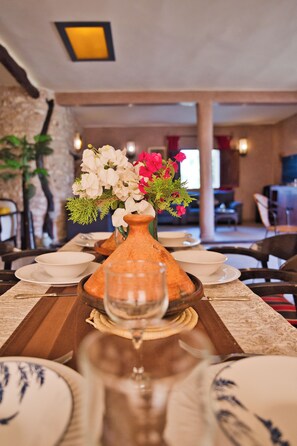 A dining table set with white plates, a glass, and a centerpiece with flowers and greenery. - Private Villa & Nature - Domaine l'Oliveraie (Essaouira)