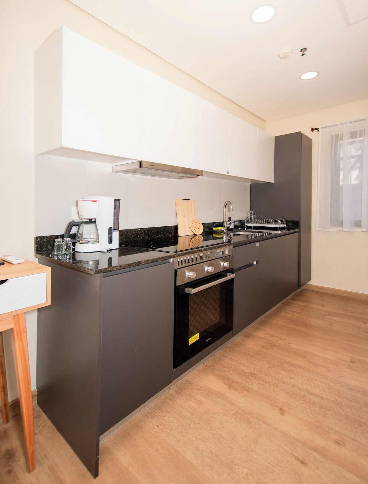 A modern kitchen with a built-in oven, a coffee maker, and a sink.