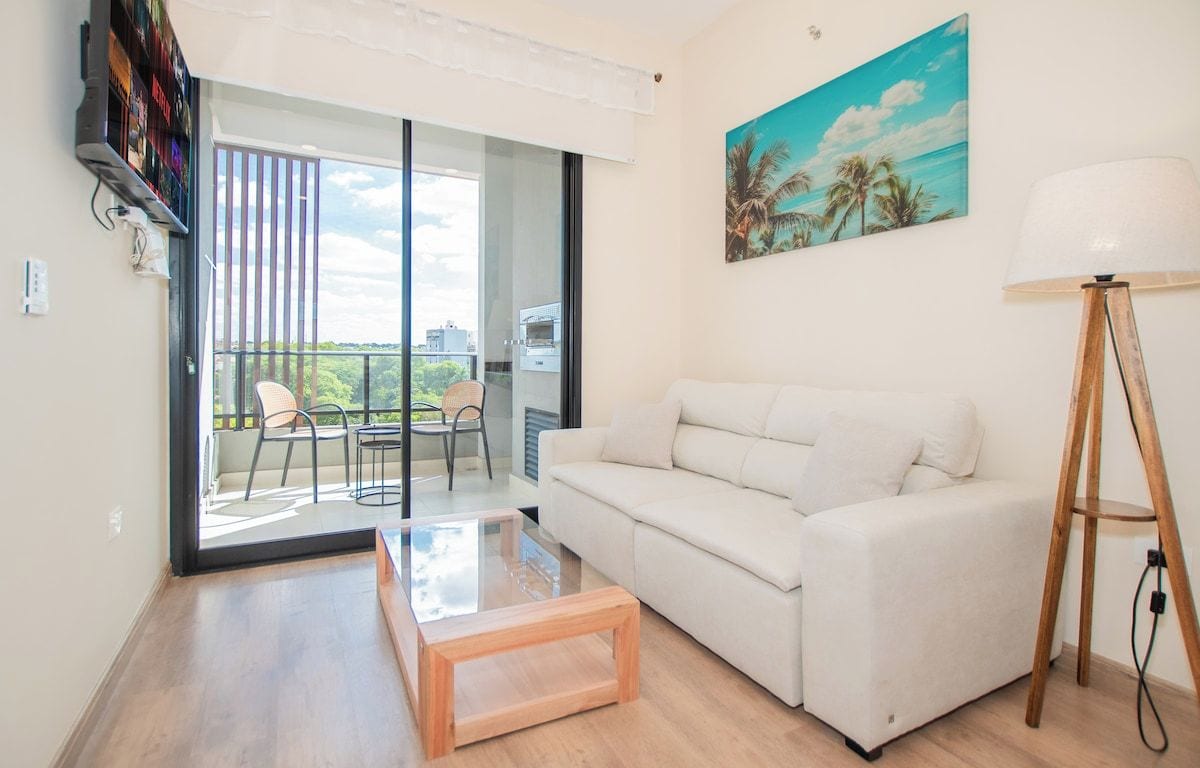 A modern living room with a white sofa, a glass coffee table, and a floor lamp.