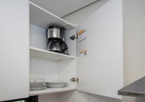 A kitchen with a coffee maker on the upper shelf and a door with a QR code. - Matrisa 1BR | Balcony, Rooftop Pool & Gym (Asunción)