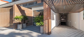 A modern building with a brick facade, large windows, and a covered outdoor area with potted plants. - Workspace Retreat Near Malls with Pool Access (Asunción)