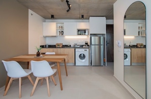 A modern kitchen with a dining area, built-in appliances, and a large mirror. - Workspace Retreat Near Malls with Pool Access (Asunción)
