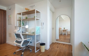 Un espace de bureau moderne avec un bureau blanc, une chaise ergonomique et une bibliothèque.