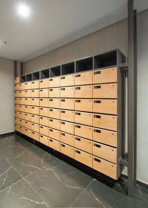 A row of wooden lockers with metal handles, arranged in a single column against a wall. - Modern 1BR in Boggiani | Pool, City Views & WiFi (Asunción)