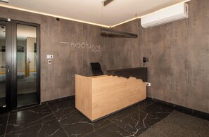 A reception desk with a wooden finish, a modern light fixture, and a wall-mounted air conditioner. - Modern 1BR in Boggiani | Pool, City Views & WiFi (Asunción)