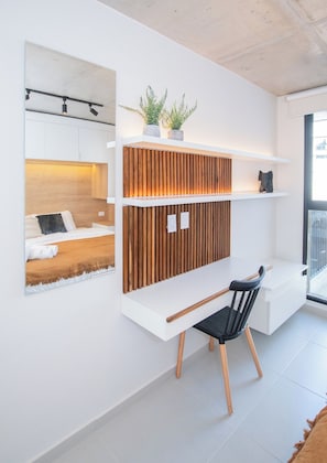 A modern room with a built-in desk, a chair, a bed, and a wall-mounted shelf with plants. - Stylish City Apartment with Balcony, Pool and Gym (Asunción)
