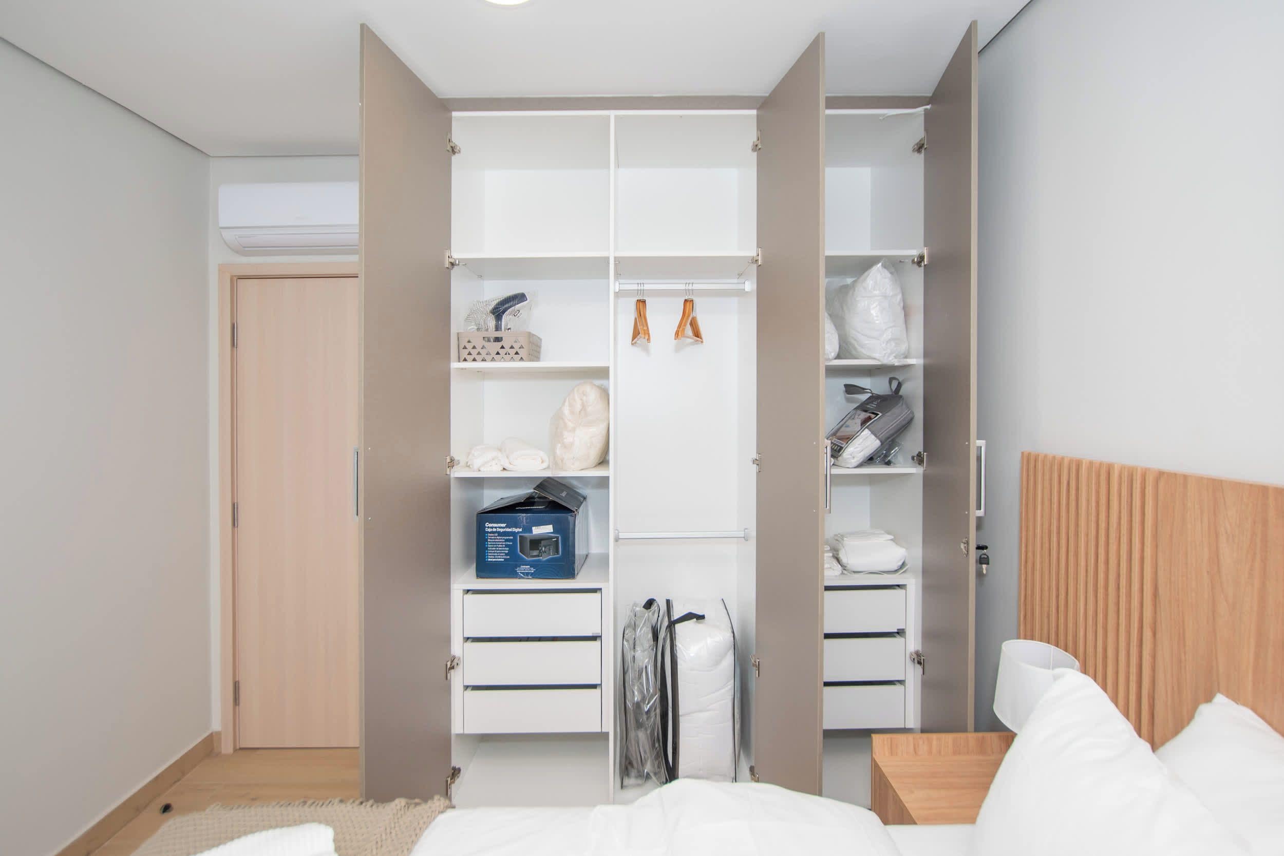 A bedroom with a bed, a wardrobe with multiple compartments, and a bedside table.