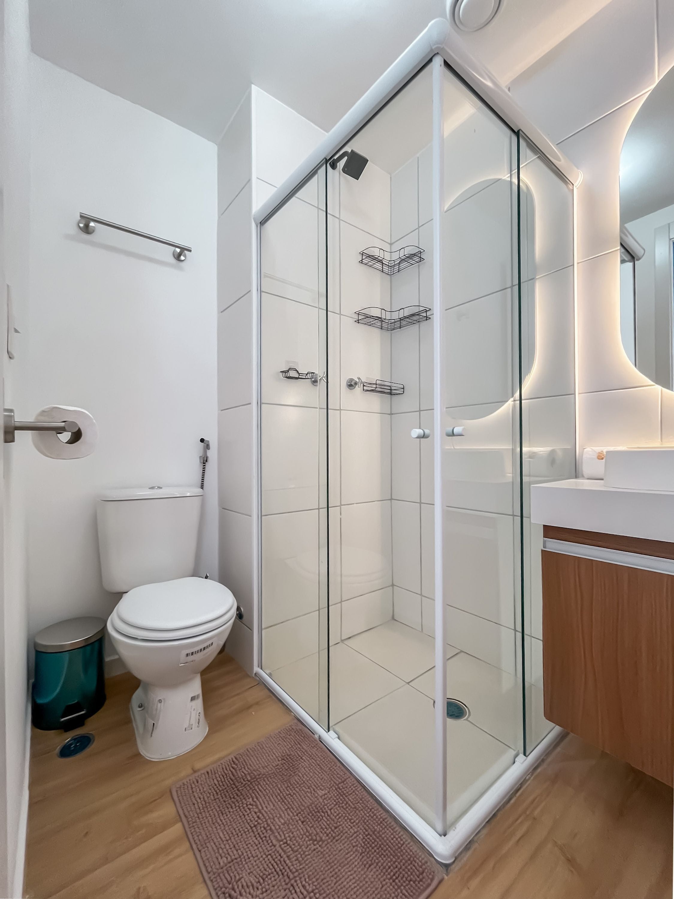 Een moderne badkamer met een douchecabine van glas, een toilet en een wastafel met een houten kastje.