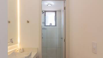 A modern bathroom with a glass shower enclosure, a wooden vanity, and a white sink.