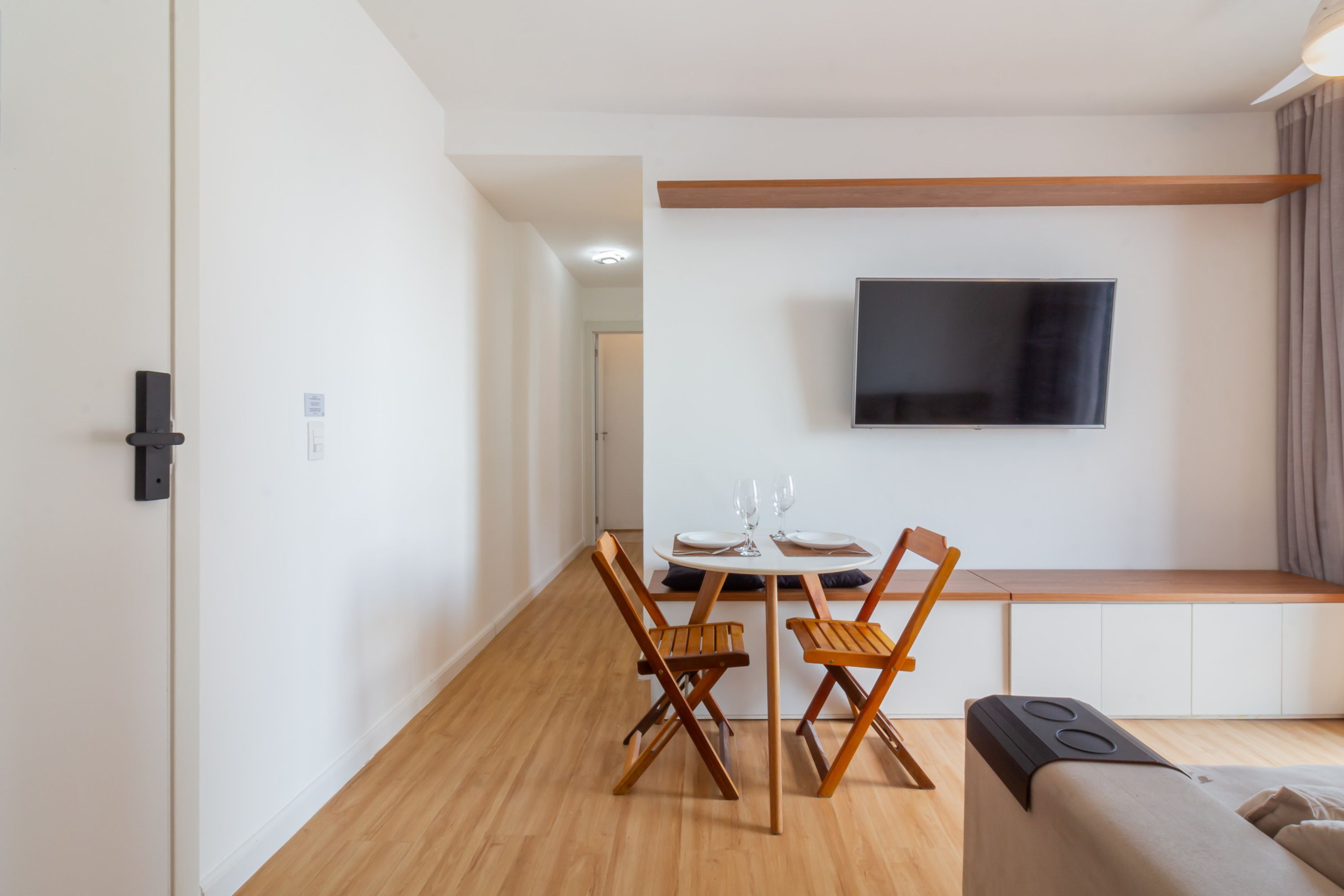 Ein zeitgemäßer Wohnraum mit Essbereich, einer Couch und einem an der Wand befestigten Flachbildfernseher.