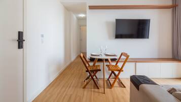 Ein zeitgemäßer Wohnraum mit Essbereich, einer Couch und einem an der Wand befestigten Flachbildfernseher.