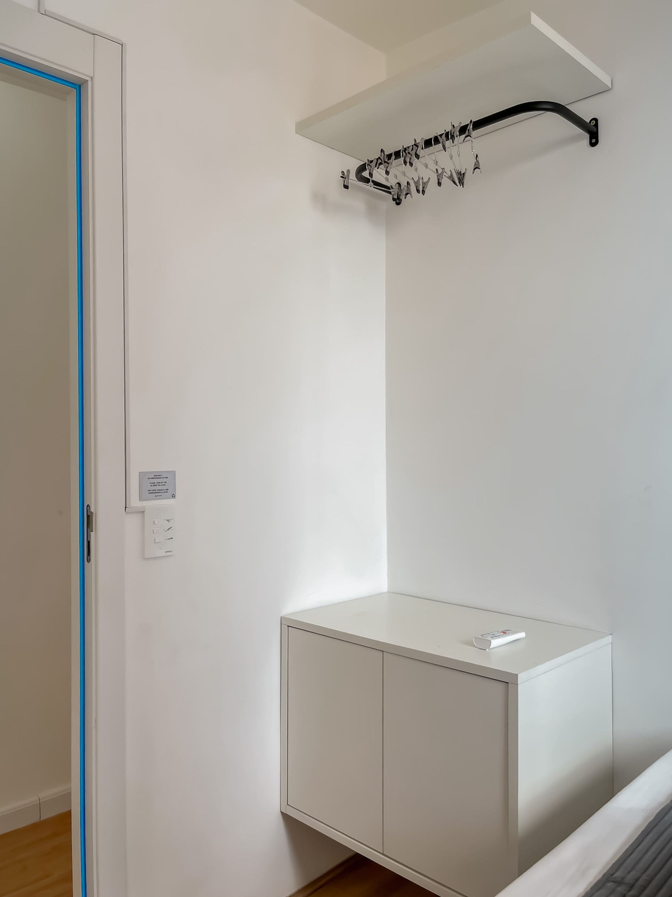 Ein Zimmer mit einem weißen Schrank, einer Tür mit blauer Umrandung und einem Deckenmontagerack.