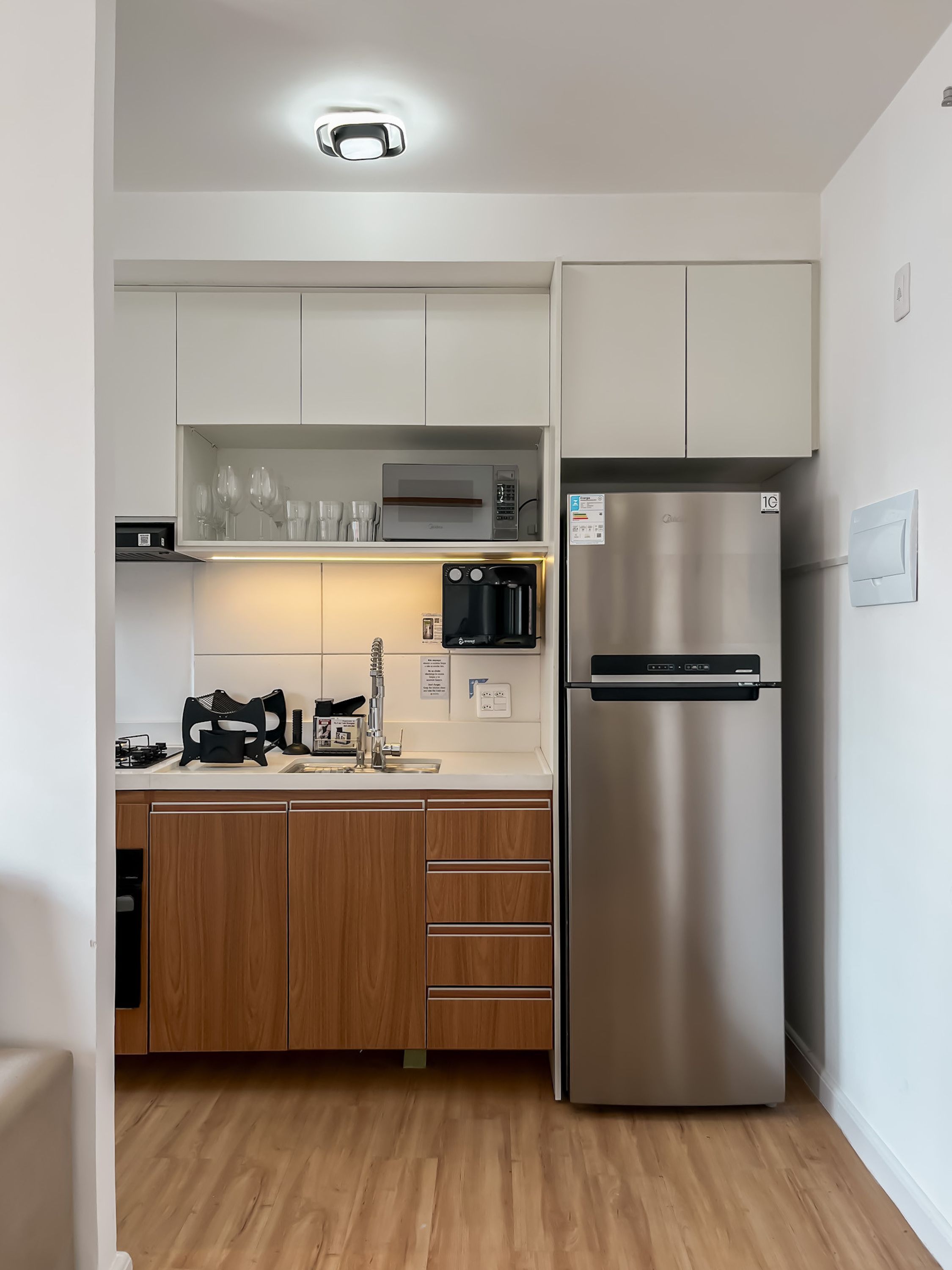 Eine moderne Küche mit weißen Schränken, einem Edelstahlkühlschrank und einer eingebauten Mikrowelle.