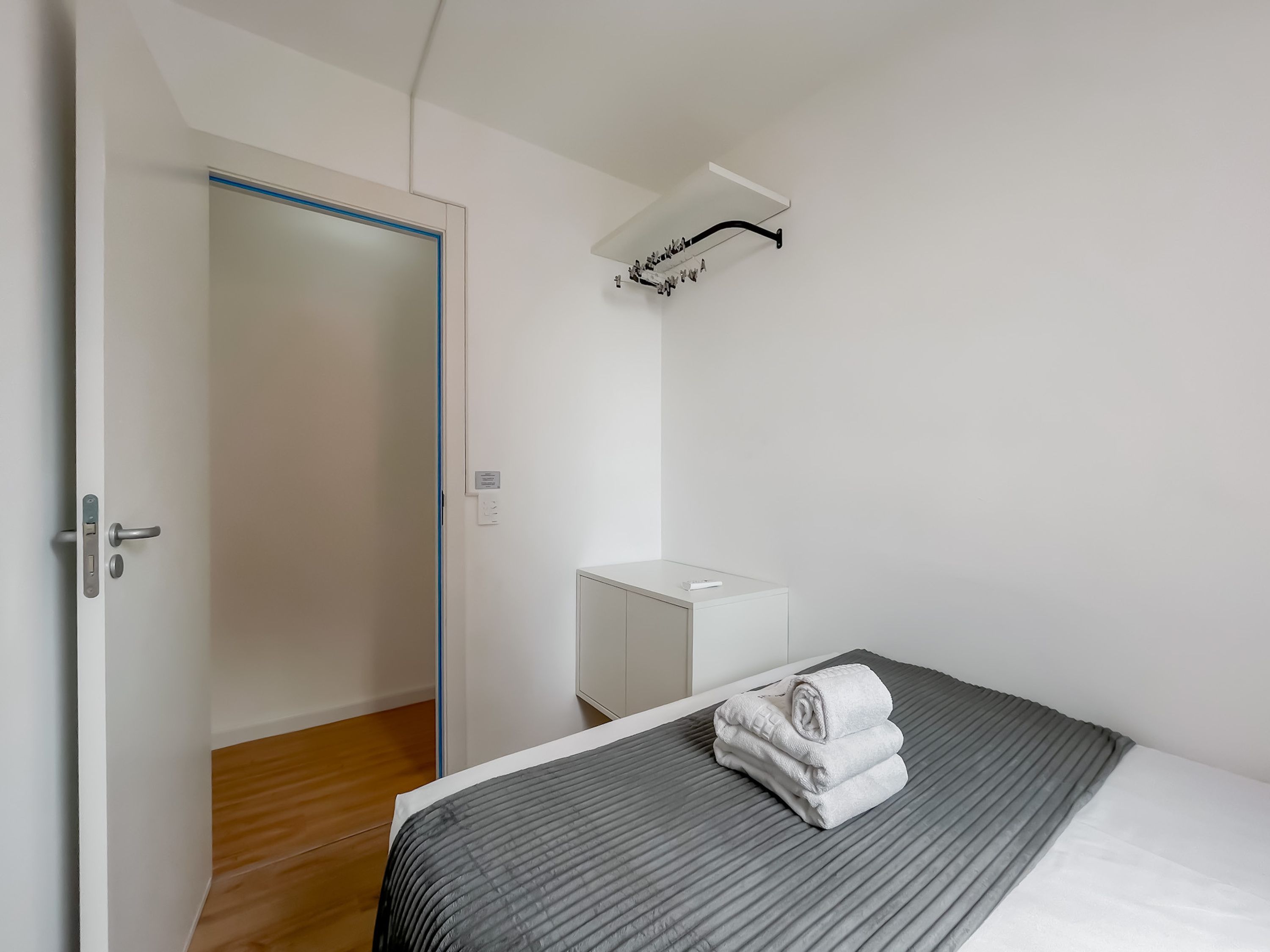 Ein Hotelzimmer mit Bett, Nachttisch, Kleiderschrank und einem Handtuch auf dem Bett.