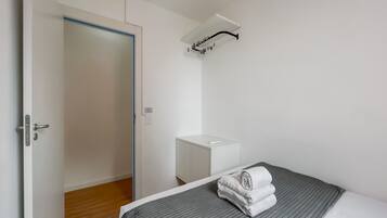Ein Hotelzimmer mit Bett, Nachttisch, Kleiderschrank und einem Handtuch auf dem Bett.