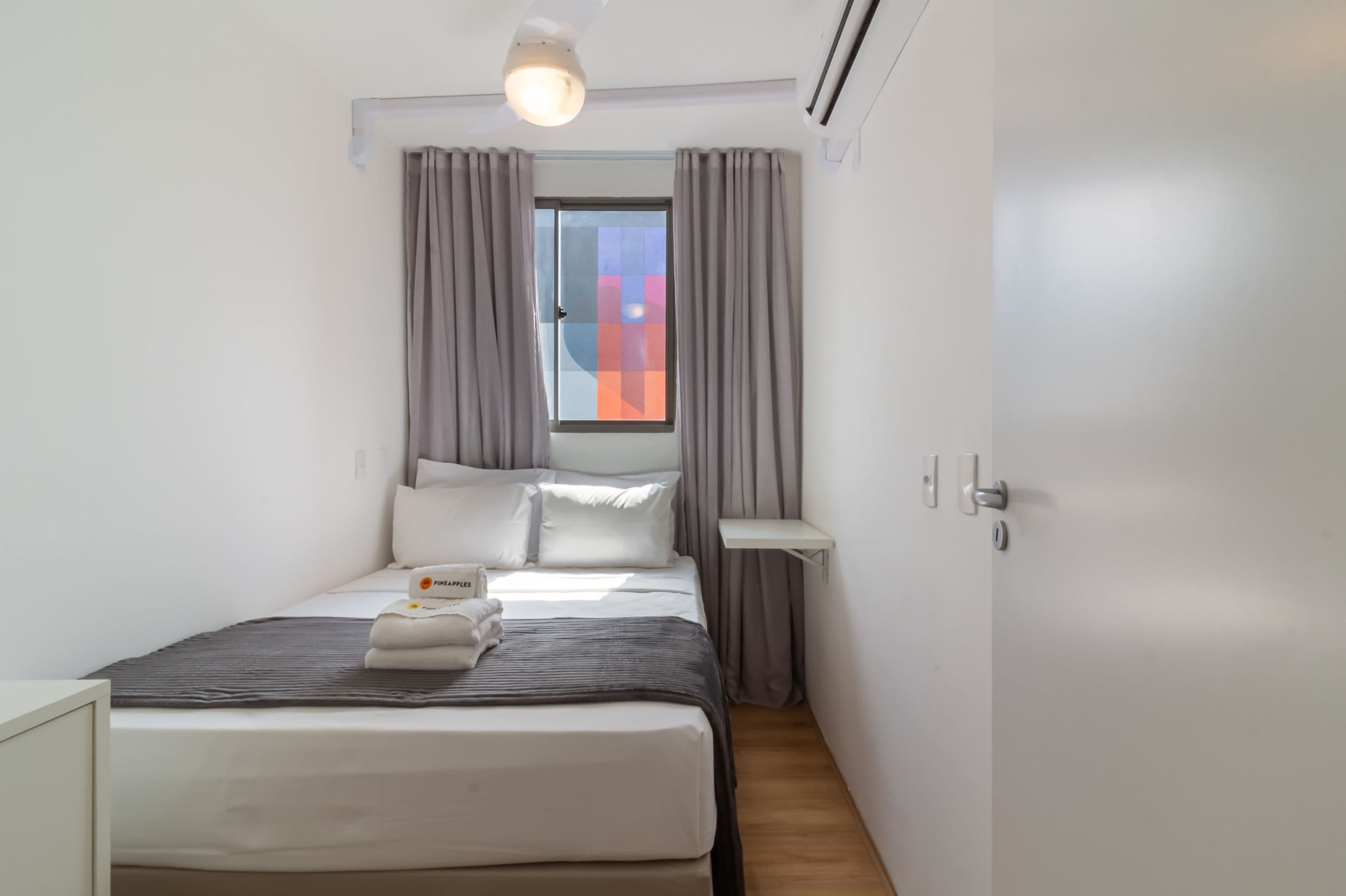 Ein modernes Schlafzimmer mit einem Bett, einem Nachttisch, einem Fenster mit Vorhängen und einer Deckenleuchte.
