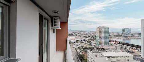 Un balcón con vista a la ciudad, que incluye un río y montañas distantes.