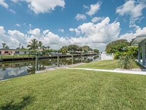 A waterfront property with a grassy lawn, a dock, and a canal. - Waterfront 3BR home with private dock, down the street from the beach! (Fort Pierce)