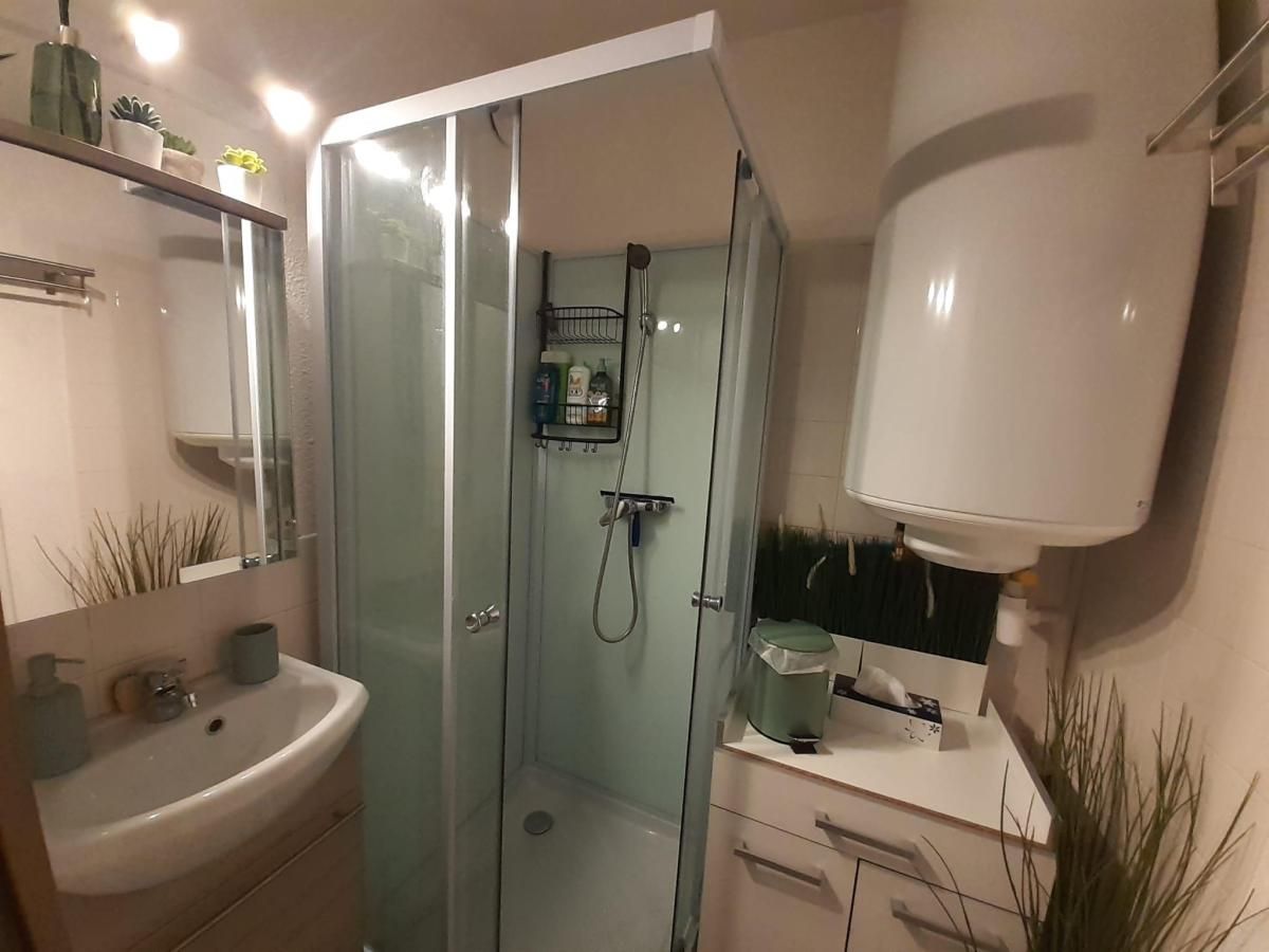 Ein modernes Badezimmer mit einer begehbaren Glasdusche, einem Waschbecken und einem Spiegel.