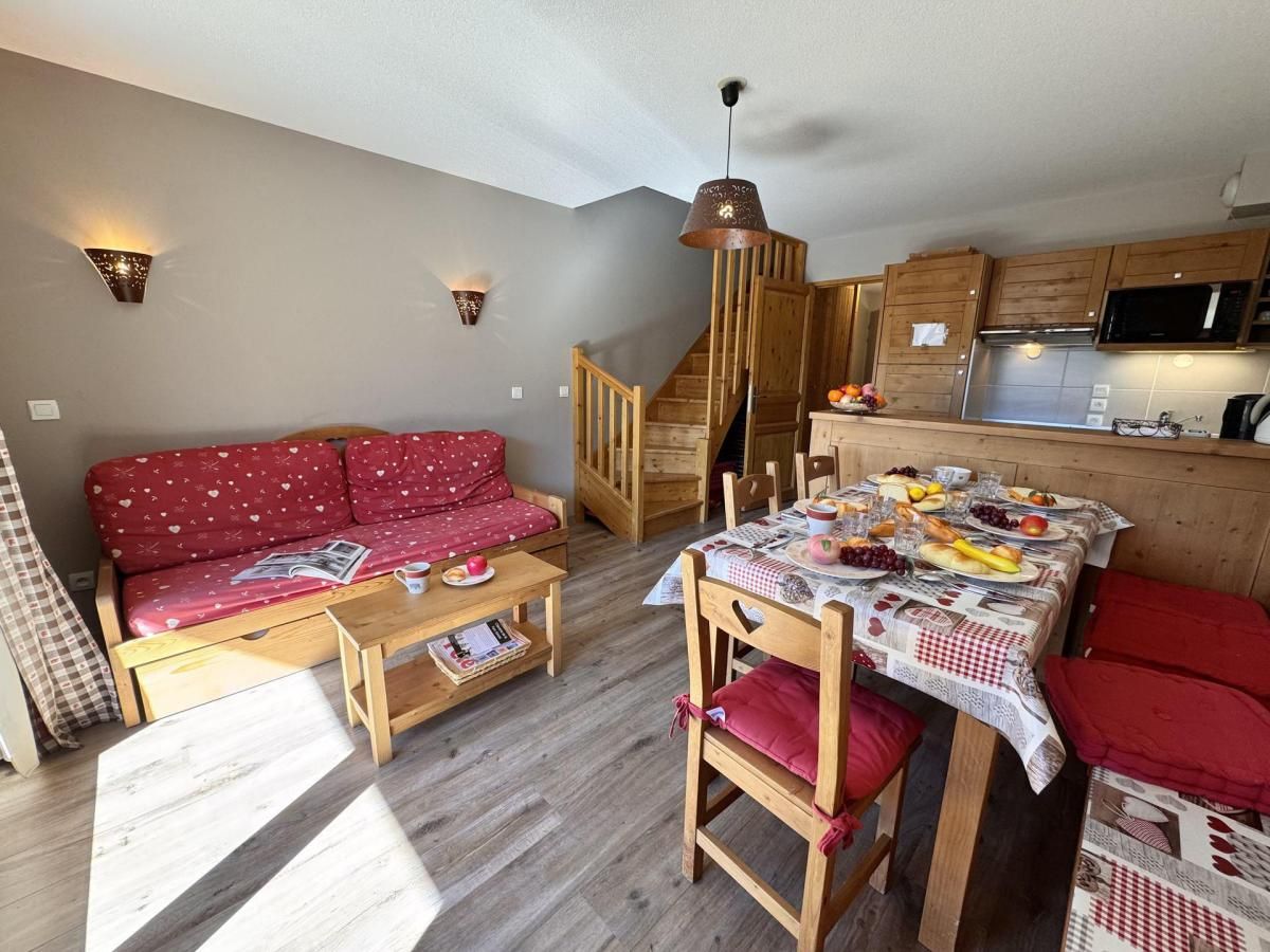 Un salon accueillant avec un canapé, une table à manger dressée et un escalier menant à la cuisine.