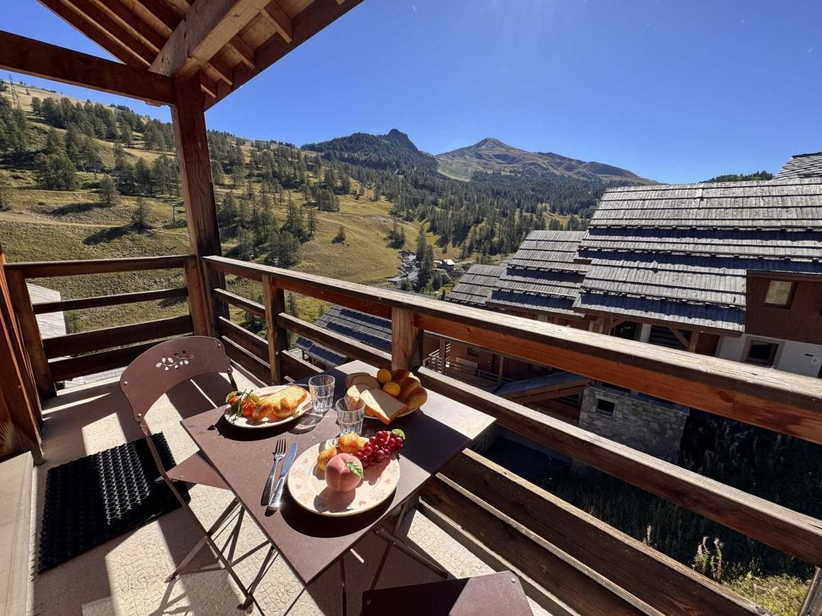 Un balcon avec une table dressée pour un repas, donnant sur un paysage montagneux.