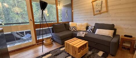A modern living room with a sofa set, a coffee table, and a large window with a view of trees.