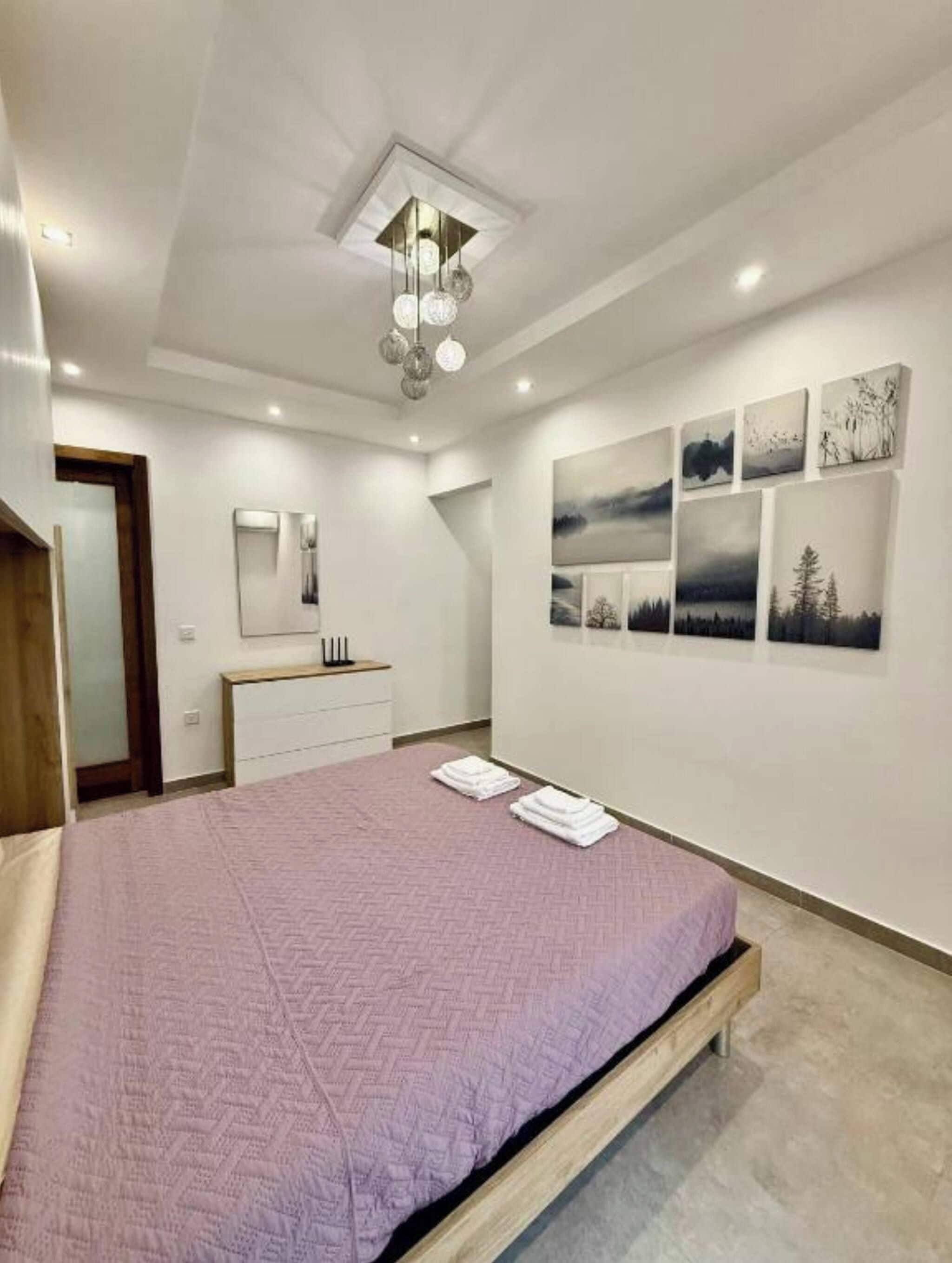A bedroom with a bed, a bedside table, a mirror, and wall art.